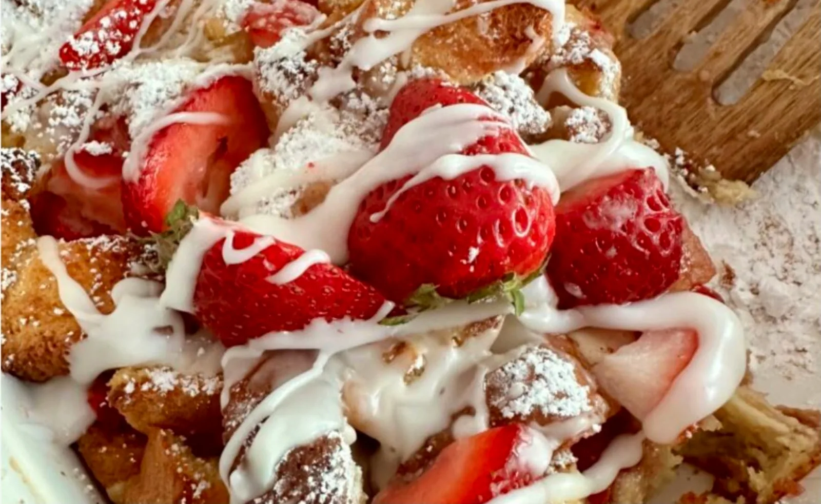 Strawberries-and-cream french toast dusted with powdered sugar and drizzled with icing