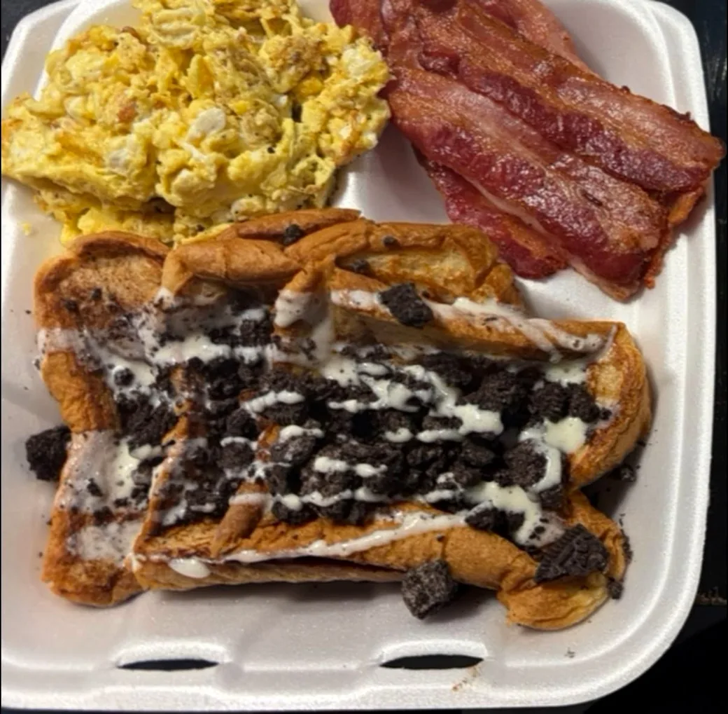Cookies-and-cream french toast drizzled with icing, served with scrambled cheese eggs and bacon