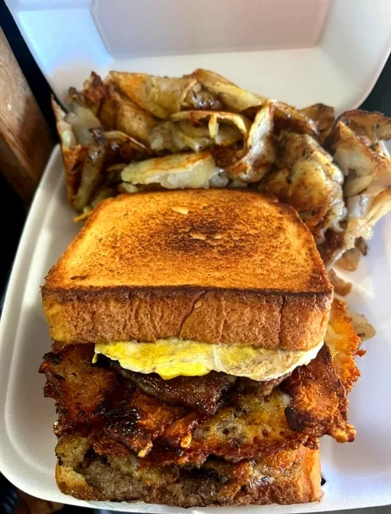 Texas toast stacked with egg, meat and fried potatoes